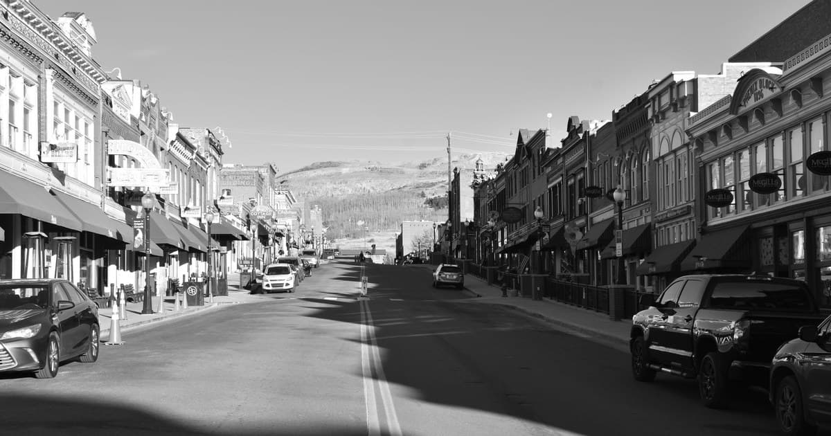 Black and white photo of a historic main street with vintage buildings and cars.