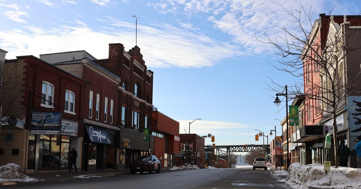 Quaint winter scene of a small town street with historic buildings and a clear blue sky.